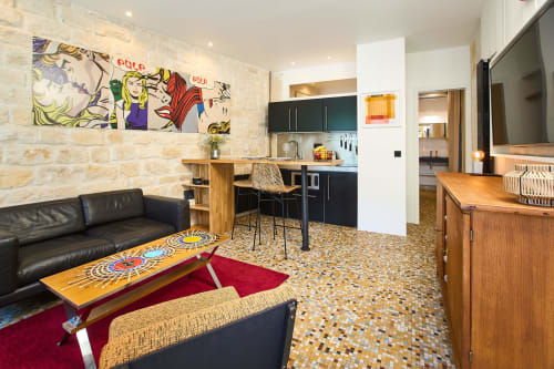 Loft moderne Boutik Boheme Paris avec mur pop art, cuisine noire, canapé cuir et sol mosaïque coloré