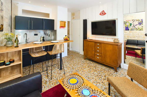 Loft parisien Boutik Boheme avec cuisine ouverte, salle à manger, TV et mobilier vintage sous un tapis géométrique coloré
