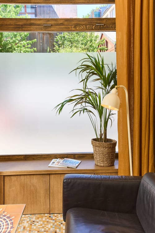 Coin lecture lumineux avec plante verte, mobilier en bois chaleureux et lecture à la fenêtre de Boutik Boheme