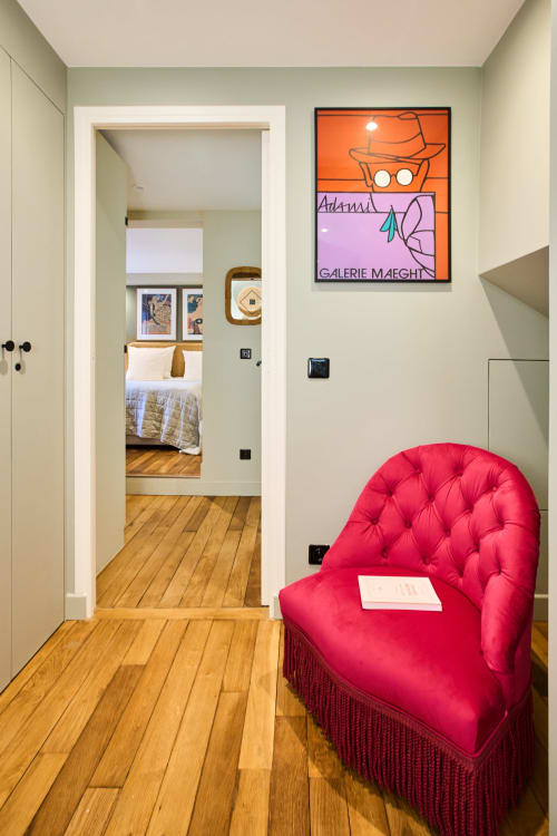 Couloir d'appartement parisien moderne avec chaise rouge vif, parquets en bois et œuvres d'art colorées chez Boutik Boheme