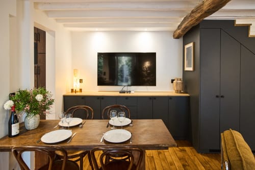 Coin repas de l'appartement parisien Le jardin Montmartre avec table en bois, meuble TV noir et téléviseur