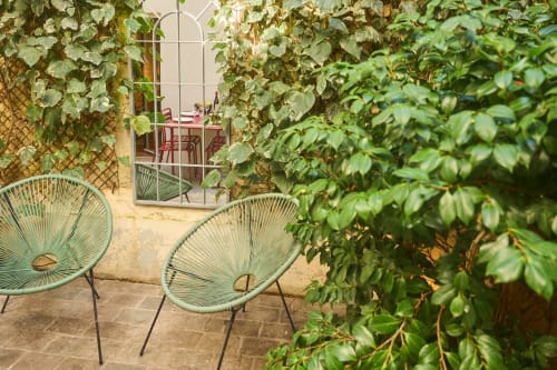 Cour verdoyante de Boutik Boheme Paris avec chaises turquoise et murs couverts de lierre