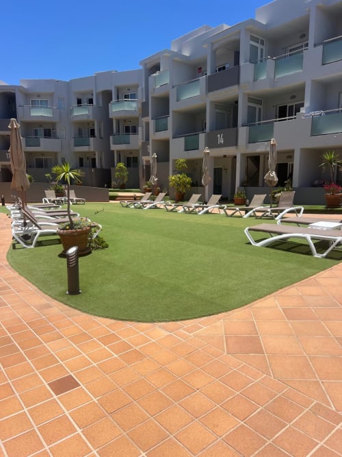Patio de FTV Holidays Homes en La Oliva con tumbonas, jardín verde y modernos apartamentos blancos