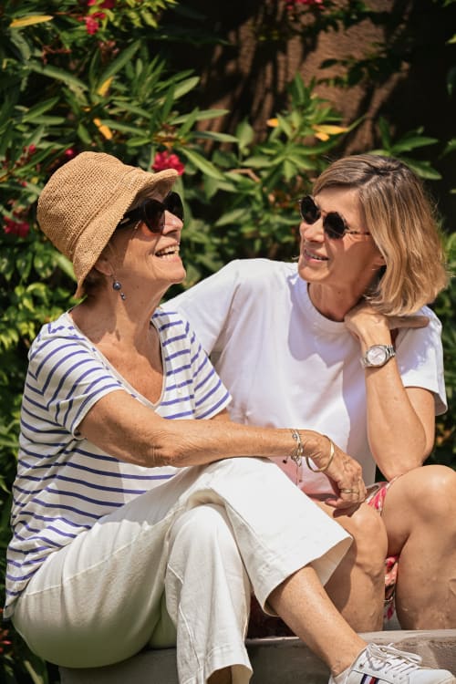 Deux femmes riant dans un jardin du Mas de la Digue, un gîte français à Châteaurenard, entourées de couleurs