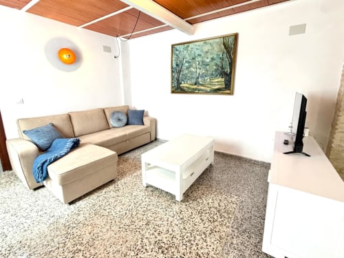 Sala de estar moderna en Marqués Urban Loft Valencia con sofá seccional beige, mesa de café blanca y terrazzo
