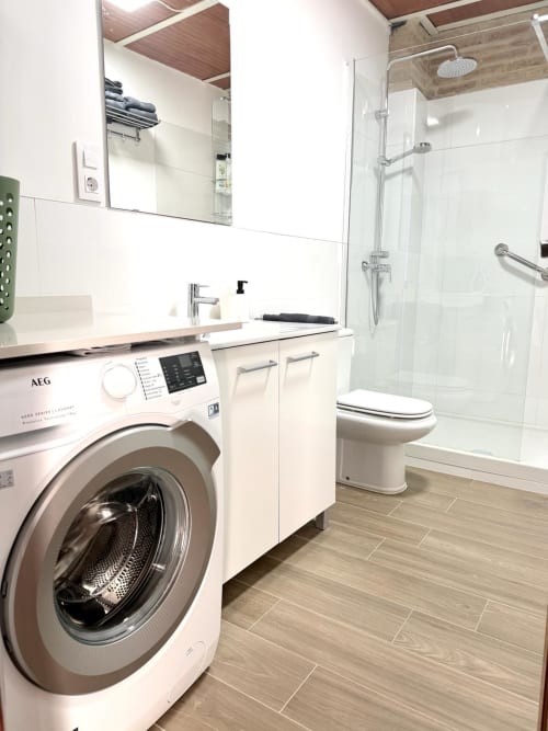 Baño moderno con lavadora, lavabo, inodoro y cabina de ducha de cristal en el apartamento Stay Gest de Valencia