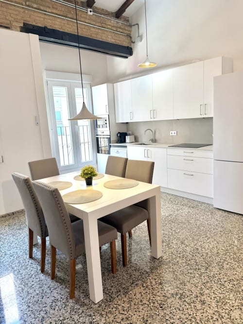 Cocina moderna de apartamento en Valencia con zona de comedor, muebles blancos, iluminación colgante y vistas a la ciudad en Stay Gest