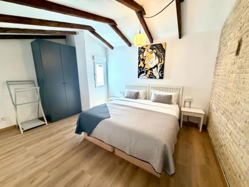 Dormitorio moderno en Marqués Urban Loft Valencia con cama doble, vigas vistas, pared de ladrillo y vista a la ciudad