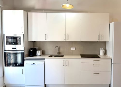 Cocina moderna blanca con electrodomésticos de acero inoxidable en apartamento Stay Gest Valencia