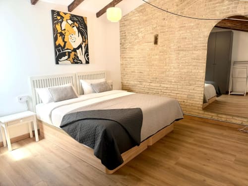 Dormitorio moderno en Marqués Urban Loft Valencia con cama de madera, paredes de ladrillo y arte abstracto