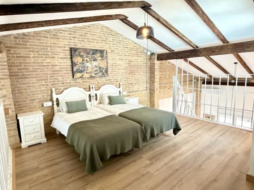 Dormitorio loft moderno con paredes de ladrillo visto, vigas de madera, camas gemelas y vistas a la ciudad en Stay Gest Valencia