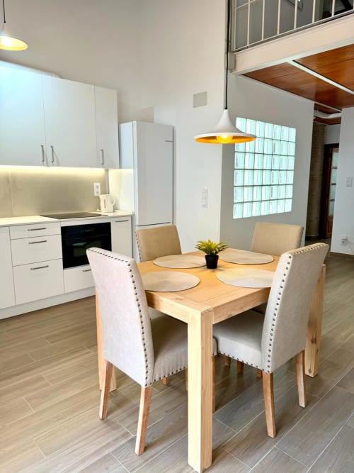 Cocina y comedor modernos en Marqués Urban Loft 2 Valencia con mesa de madera, sillas tapizadas y vistas a la ciudad