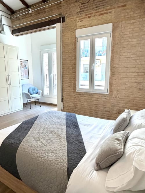 Dormitorio tipo loft moderno en Valencia con paredes de ladrillo, vistas a la ciudad, cama doble y sala de estar en el Stay Gest hotel