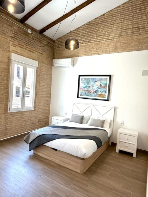 Dormitorio moderno en loft Stay Gest Valencia con ladrillos vistos, vigas de madera, cama queen y vistas a la ciudad