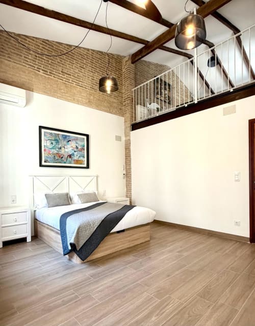 Dormitorio moderno con loft entresuelo, paredes de ladrillo, vigas de madera y suelos de espiga en Marqués Urban Loft, Valencia