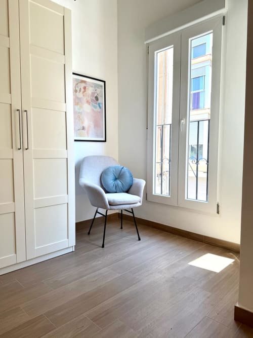 Rincón de dormitorio moderno en Marqués Urban Loft 2 Valencia con sillón gris, armario blanco y puertas hacia el balcón con vistas