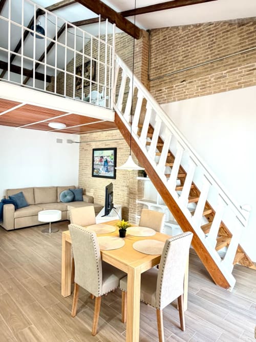 Comedor del Marqués Urban Loft 2 Valencia con mesa de madera, paredes de ladrillo y escalera moderna
