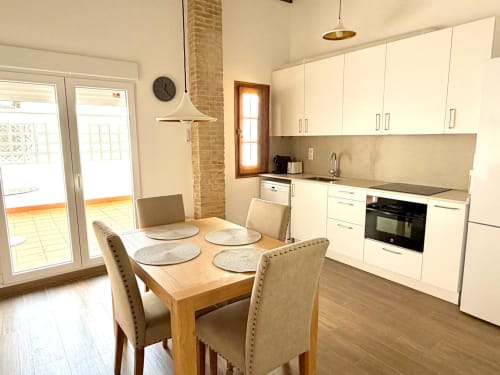 Cocina y comedor modernos en Marqués Urban Loft 2, apartamento en Valencia con muebles blancos y mesa de madera