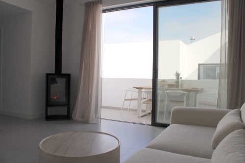 Modern villa living room with fireplace, sea view terrace, and contemporary furnishings in Bordeira, Portugal