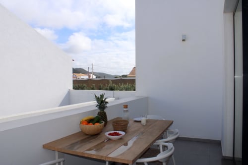 Private terrace at Casa Mareta villa in Bordeira with wooden dining table, pineapple and fruit bowl, mountain views