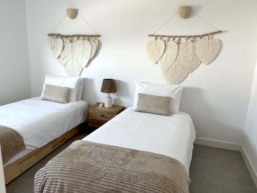 Twin bedroom at Casa Mareta villa in Bordeira with white linens, macramé wall hangings, and sea views near Porto