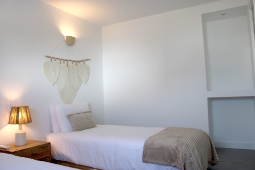 Bright modern bedroom at Casa Mareta villa in Bordeira with white walls, single bed, wooden nightstand, and decorative leaf