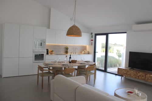 Modern open-plan living area in Casa Mareta villa with dining table, kitchen, and sea views near Bordeira