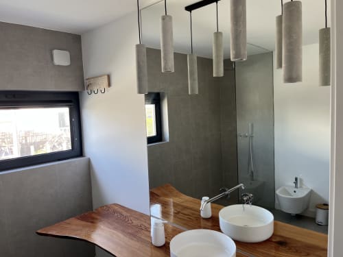 Modern bathroom in Casa Mareta villa with dual sinks, concrete pendant lights, gray tile shower, and wooden vanity in