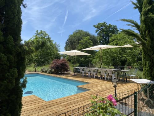 Baccara Lodge pool deck with wooden terrace, lounge chairs, umbrellas, and lush gardens in Arengosse
