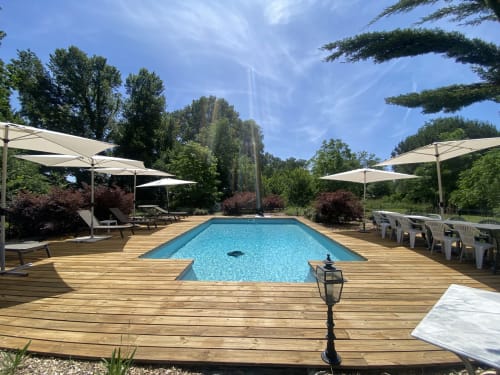 Baccara Lodge pool area in Arengosse with blue swimming pool, wooden deck, white umbrellas, and lounge chairs surrounded by