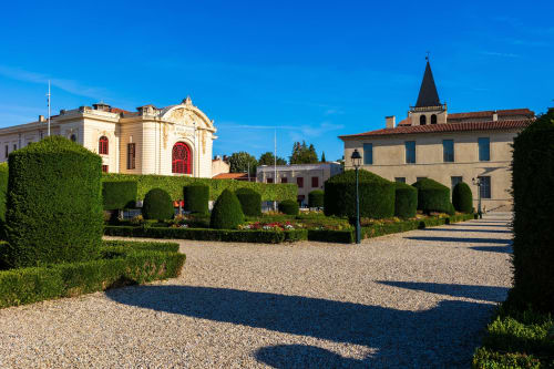 Cour élégante du Le 1 Péraudel à Castres avec haies soignées, allées gravillonnées et architecture historique.