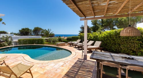 Terraza de piscina Villas Etnia en Sant Lluís con vistas al mar, tumbonas y pérgola