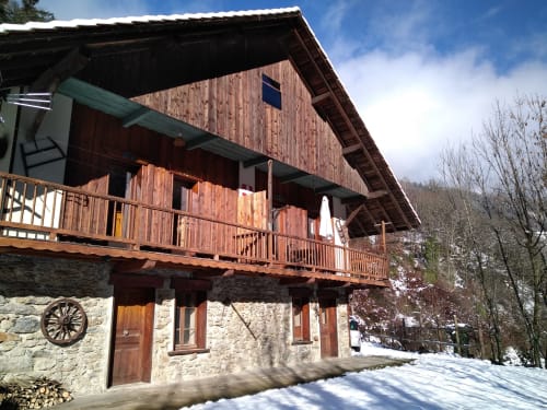 Chalet Gîte Les Boleros à Queige avec balcon en bois, soubassement en pierre et vue sur les montagnes en hiver