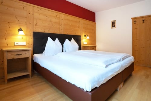 Spacious bedroom at Rusctlea Apartments in Selva di Valgardena with wooden furnishings, white bedding, and mountain views