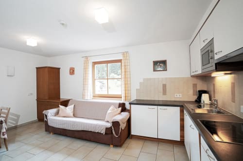 Zwei-Zimmer-Apartment Rusctlea in Selva di Valgardena mit Sofa, Küche und Bergblickfenster