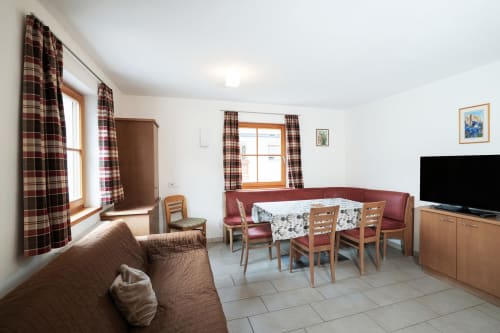 Geräumiges Zweizimmer-Apartment im Rusctlea Apartments in Selva di Valgardena mit Wohnbereich, Esstisch und Flachbildschirm