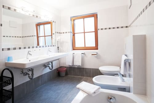 Modernes Badezimmer in der Rusctlea Apartments mit Doppelwaschbecken, Toilette, Bidet und Holzrahmenfenster in Selva di Valgardena