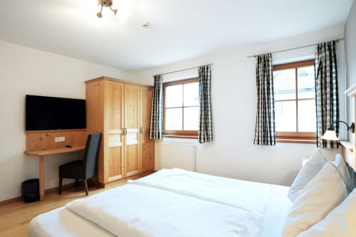 Helles Schlafzimmer in der Rusctlea Apartments mit Doppelbett, Holzschrank, Schreibtisch mit TV und Bergblick aus den Fenstern