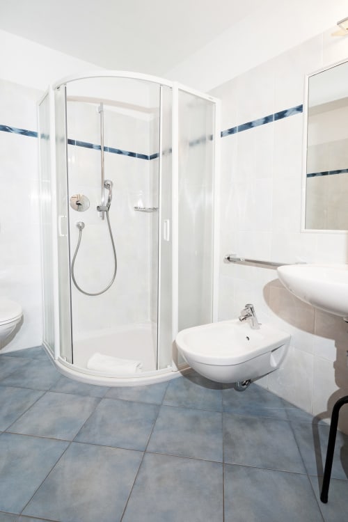 Modernes Badezimmer mit begehbarer Dusche, weißem Waschbecken und Bidet in den Rusctlea Apartments in Selva di Valgardena