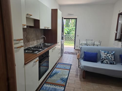 Cucina moderna e zona living dell'appartamento Villargentina a San Felice Circeo con divano, stufa a gas e accesso al giardino