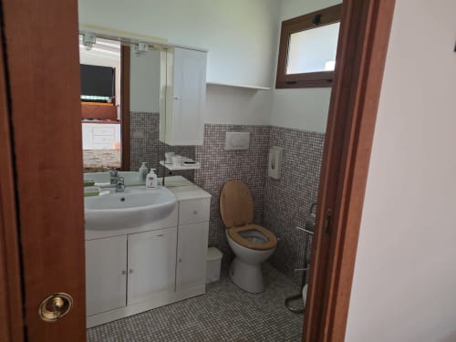 Bagno dell'appartamento Villargentina, San Felice Circeo, con lavabo bianco, wc e dettagli in piastrelle a mosaico