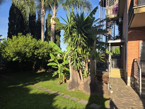 Giardino della guest house Villargentina a San Felice Circeo con palme e vialetto pavimentato che conduce all'ingresso