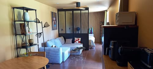 Modern open-plan living area at Domaine Alga B&B in Bourg-Charente with blue sofa, shelf unit, and kitchenette