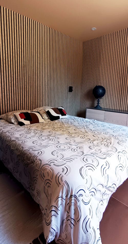Chambre moderne au Domaine Alga avec murs d'accent en bois vertical, literie à motifs et mobilier contemporain