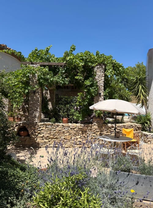 Terrasse en pierre charmante à La Closerie B&B à La Redorte avec lierre grimpant, parasol blanc et jardin de lavande