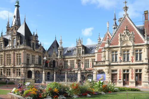 Historic ornate mansion with turrets and colorful flower gardens in Ecrainville, France