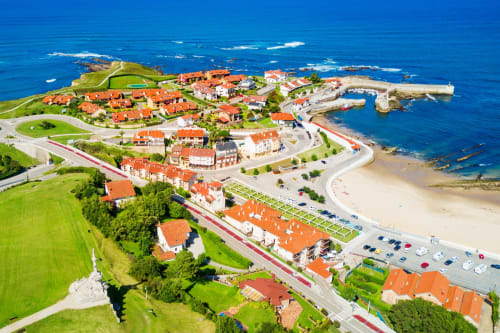 Posada Torre del Milano in Comillas, Spain - Aerial view of coastal hotel with orange roofs, beach, and blue sea