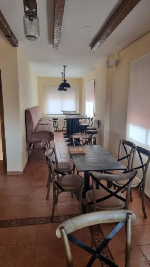 Zona de comedor y salón en villa Finca El Arroyo con vigas vistas, suelos de barro y mobiliario rústico en Alcaraz