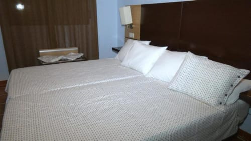 Dormitorio principal de villa de 2 habitaciones en Finca El Arroyo, Alcaraz con cama queen, almohadas blancas, ropa de cama estampada, oscuro