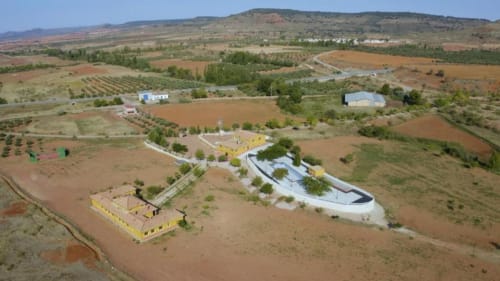 Vista aérea de la villa Finca El Arroyo en Alcaraz con edificios amarillos distintivos, estructuras blancas y campos agrícolas